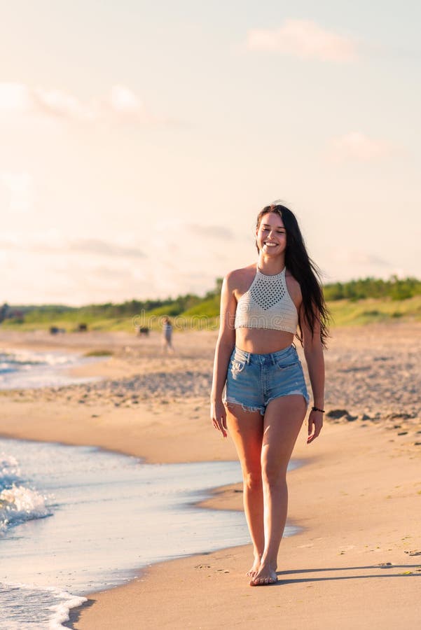 Ensam ung kvinna som går på stranden på stranden på stranden på stranden på modet och som är avslappnad och går nära sommarhavet royaltyfri fotografi