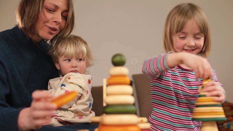 Enseignant joue aux pyramides avec des enfants sur la table. elle tient le bébé dans ses bras. banque de vidéos