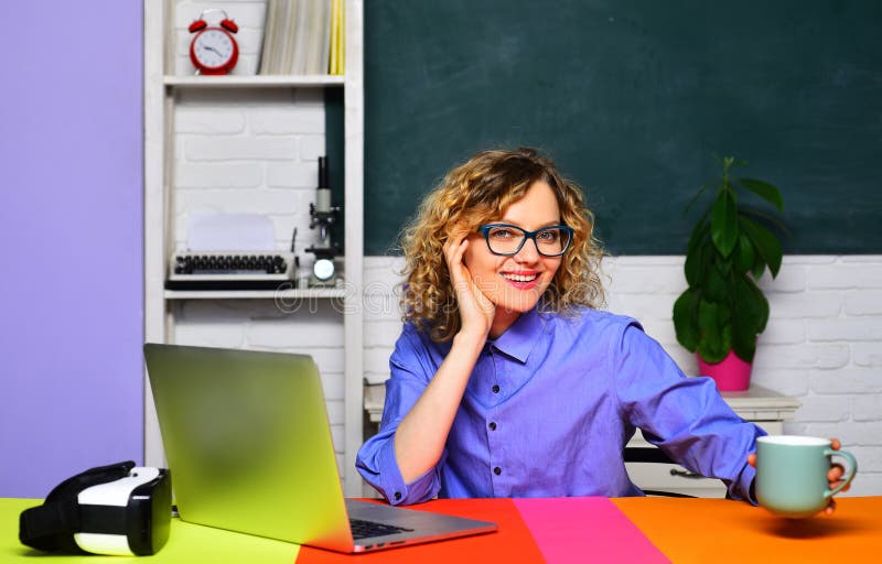 Enseignant souriant assis au bureau en classe avec pause café. Enseignante dans les lunettes avec tasse de thé image libre de droits