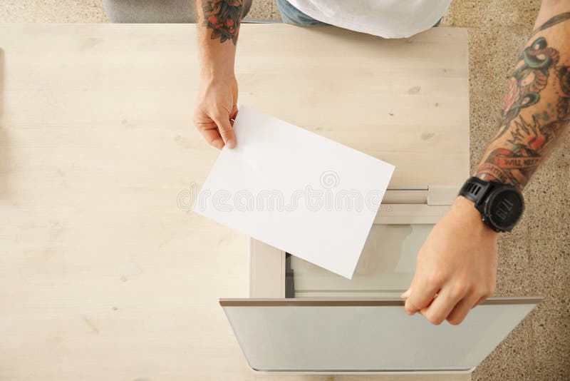 Hands open a scanner tray and put sheet of paper to scan a document on home multifunctional electronic device, isolated on white wooden table, top view. Hands open a scanner tray and put sheet of paper to scan a document on home multifunctional electronic device, isolated on white wooden table, top view