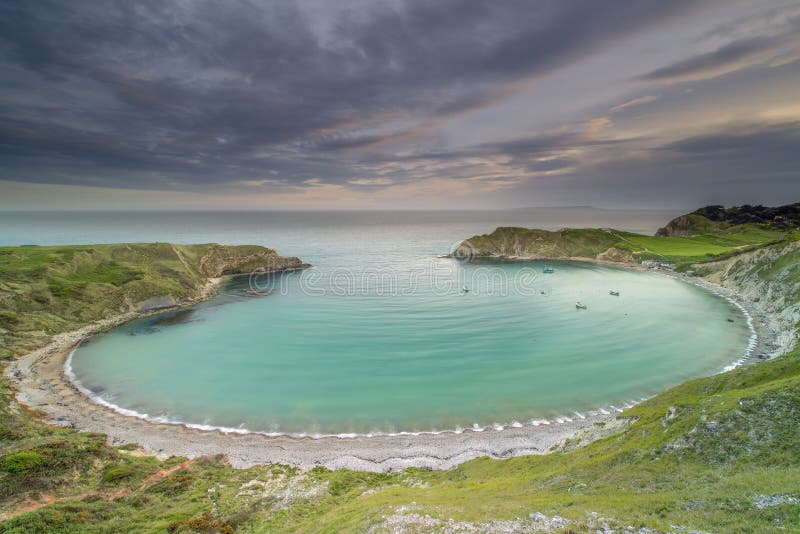 Ensenada de Lulworth en la costa jurásica de Dorset en la puesta del sol imágenes de archivo libres de regalías Ensenada de Lulworth en la costa jurásica de Dorset en la puesta del sol imágenes de archivo libres de regalías