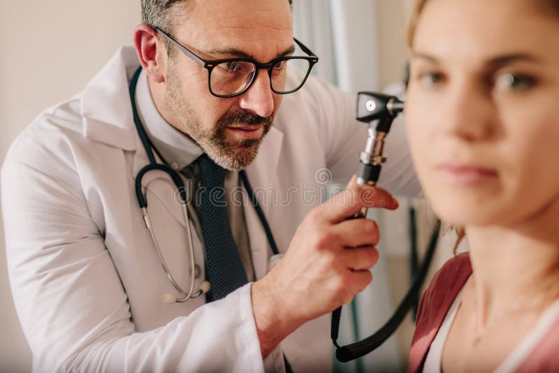 ENT arts die oor met oorspiegel van vrouwenpatiënt controleren