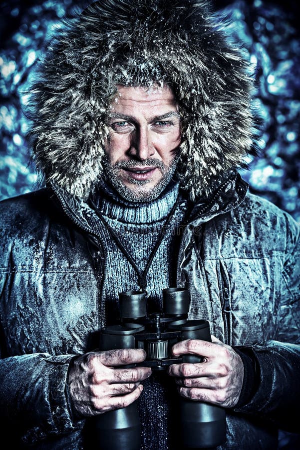 Handsome brutal man dressed in winter clothes covered with frost looking through binoculars. Handsome brutal man dressed in winter clothes covered with frost looking through binoculars.