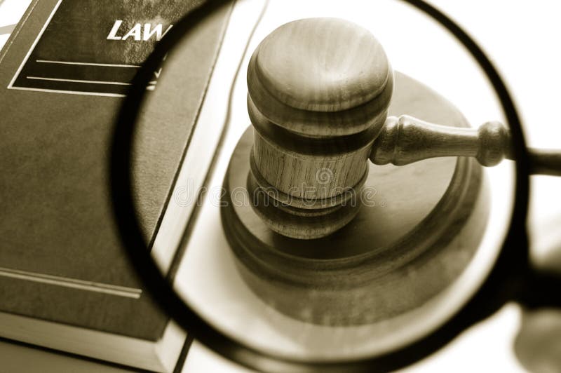 Magnifying glass examining a judges court gavel, with law book. Magnifying glass examining a judges court gavel, with law book