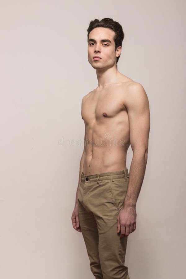 Ente senza camicia del modello del giovane che posa i pantaloni fotografie stock Ente senza camicia del modello del giovane che posa i pantaloni fotografie stock