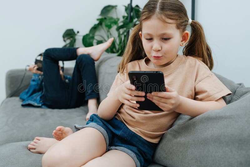 Entertained Girl with Two Pony Tail Watching Her Phone on a Couch Stock ...