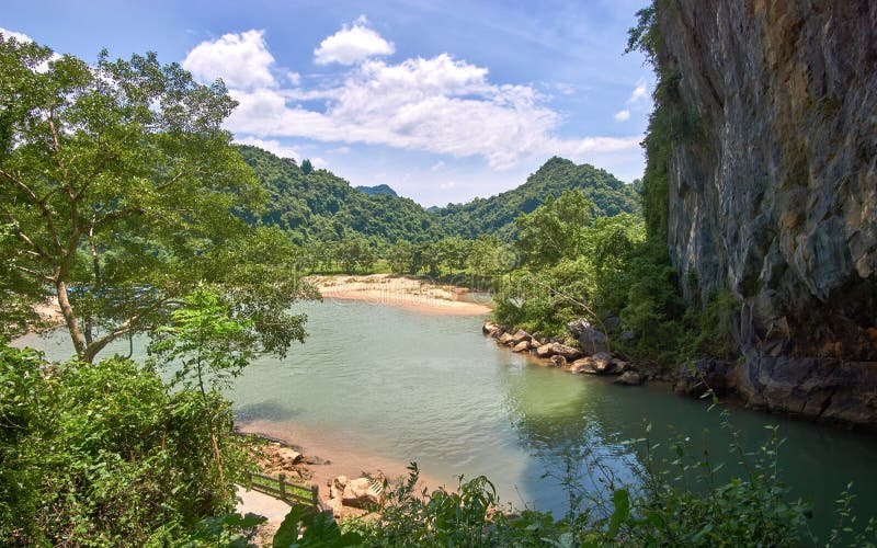 Entrada a la cueva de Phong Nha con claro un río en la cueva y las montañas en el fondo Phong Nha KE golpea la región imágenes de archivo libres de regalías Entrada a la cueva de Phong Nha con claro un río en la cueva y las montañas en el fondo Phong Nha KE golpea la región imágenes de archivo libres de regalías