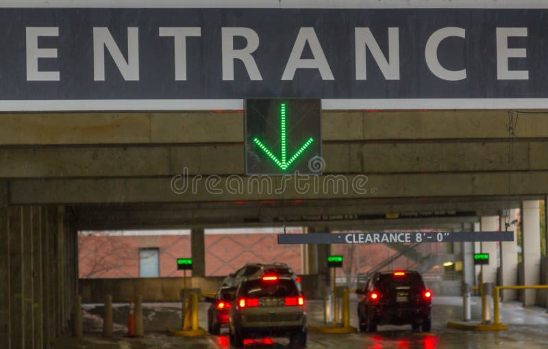 Entrance sign with a large green arrow pointing vehicles to a large city parking garage. Entrance sign with a large green arrow pointing vehicles to a large city parking garage.