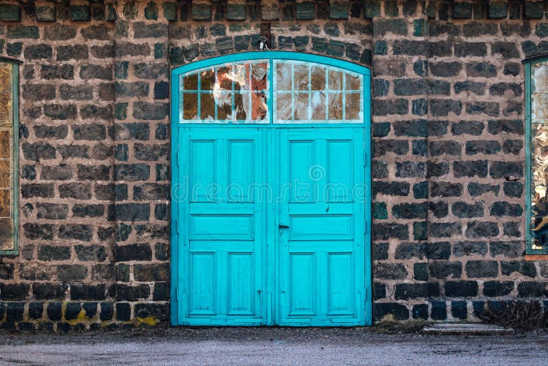 Entrance door to an old steel mill, building made of cinder stone. Turquoise entrance door to a very old steel mill building, made of cinder stones Located in stock photo Entrance door to an old steel mill, building made of cinder stone. Turquoise entrance door to a very old steel mill building, made of cinder stones Located in stock photo