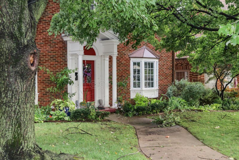 Entrance of nice brick house with bay windows after a storm that left branches and leaves littered over sidewalk and yard royalty free stock photos Entrance of nice brick house with bay windows after a storm that left branches and leaves littered over sidewalk and yard royalty free stock photos
