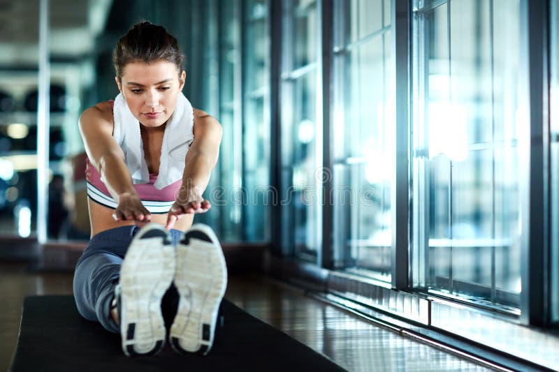 Entrar en una buena franja de preentrenamiento. una atractiva joven que pasa por su rutina de warmup en el gimnasio. foto de archivo libre de regalías