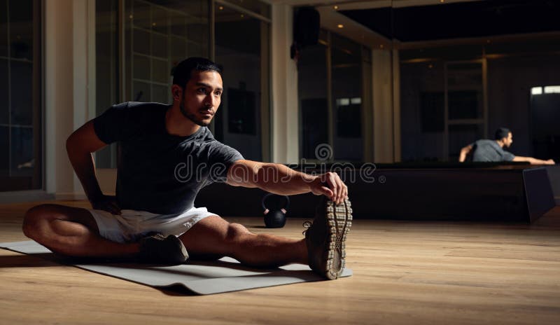 Entrar en una sólida extensión. toma completa de un apuesto joven atleta pasando por su rutina de warmup en fotos de archivo