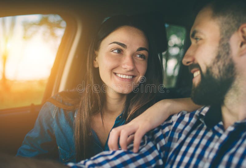 Entraînement soigneux Beaux jeunes couples se reposant sur les sièges de passager plan et souriant tandis qu'homme bel conduisant image libre de droits Entraînement soigneux Beaux jeunes couples se reposant sur les sièges de passager plan et souriant tandis qu'homme bel conduisant image libre de droits