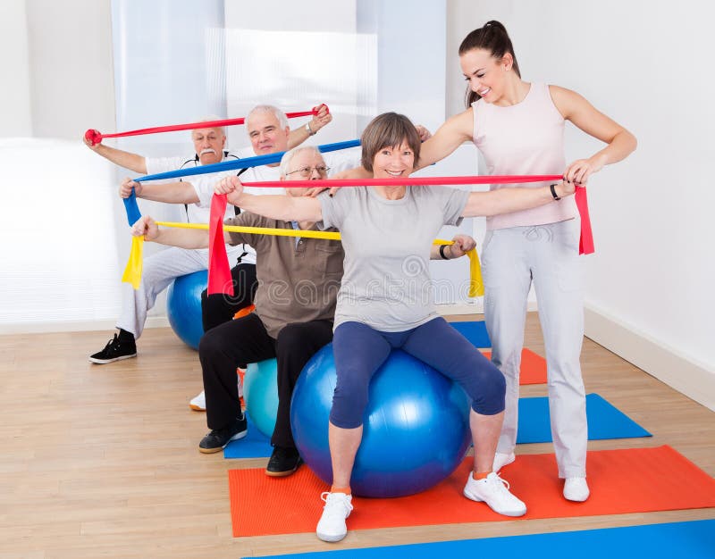 Entraîneur aidant les personnes supérieures au gymnase photos libres de droits Entraîneur aidant les personnes supérieures au gymnase photos libres de droits