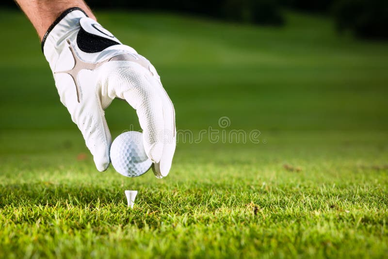 Hand hold golf ball with tee on course, close-up. Hand hold golf ball with tee on course, close-up