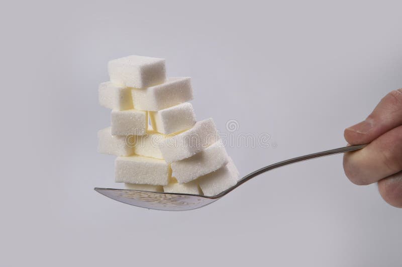 Entregue guardar a colher com a pilha de cubos do açúcar empilhou a nutrição insalubre, fazem dieta e adoçam o conceito do apego imagem de stock Entregue guardar a colher com a pilha de cubos do açúcar empilhou a nutrição insalubre, fazem dieta e adoçam o conceito do apego imagem de stock