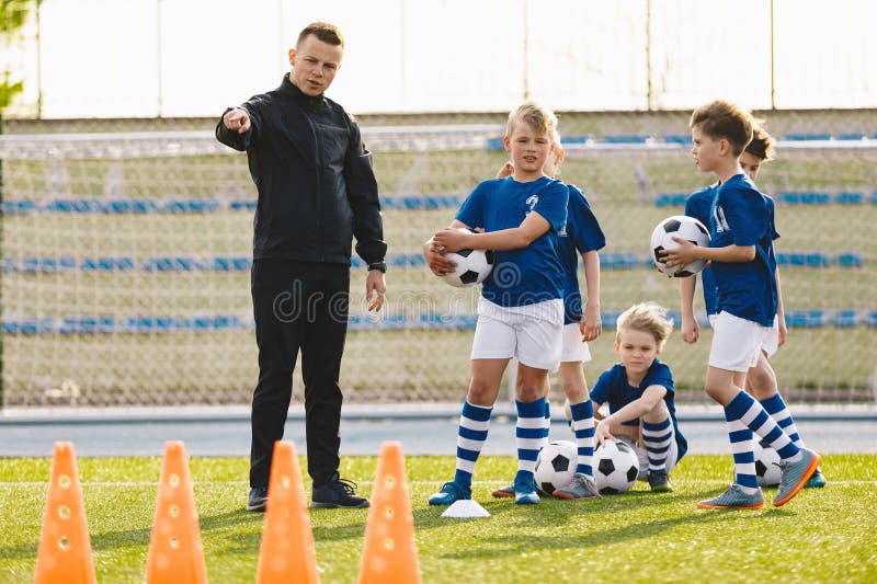 Entrenadores de equipos juveniles entrenan a escolares en fútbol. educación en fútbol para niños. clase de educación física para l foto de archivo libre de regalías