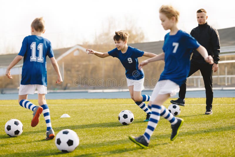 Entrenamiento de fútbol para escolares. clase de educación física para niños. entrenador joven con niños en equipo en unidad de en fotografía de archivo
