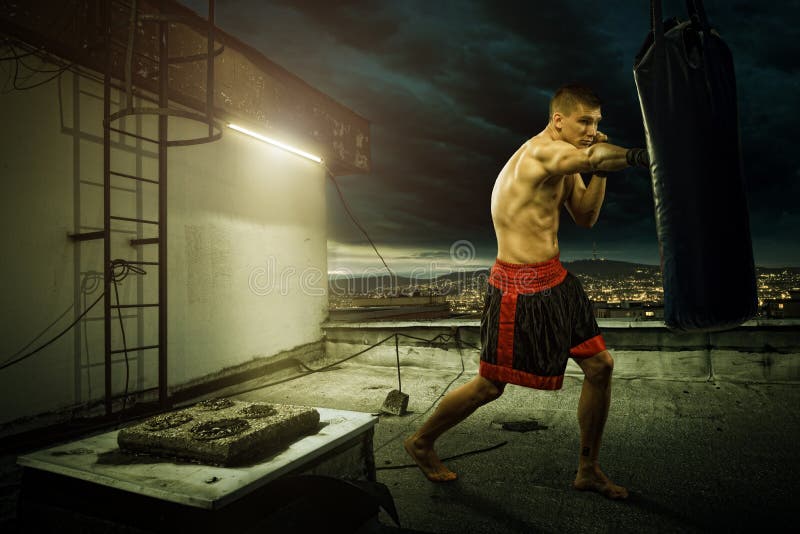 Entrenamiento del boxeo del hombre joven, encima de la casa sobre la ciudad fotos de archivo Entrenamiento del boxeo del hombre joven, encima de la casa sobre la ciudad fotos de archivo