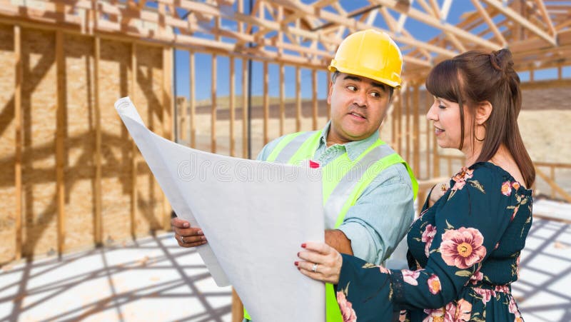 Entrepreneur masculin hispanique parlant avec le client féminin au-dessus des plans de modèle au chantier de construction
