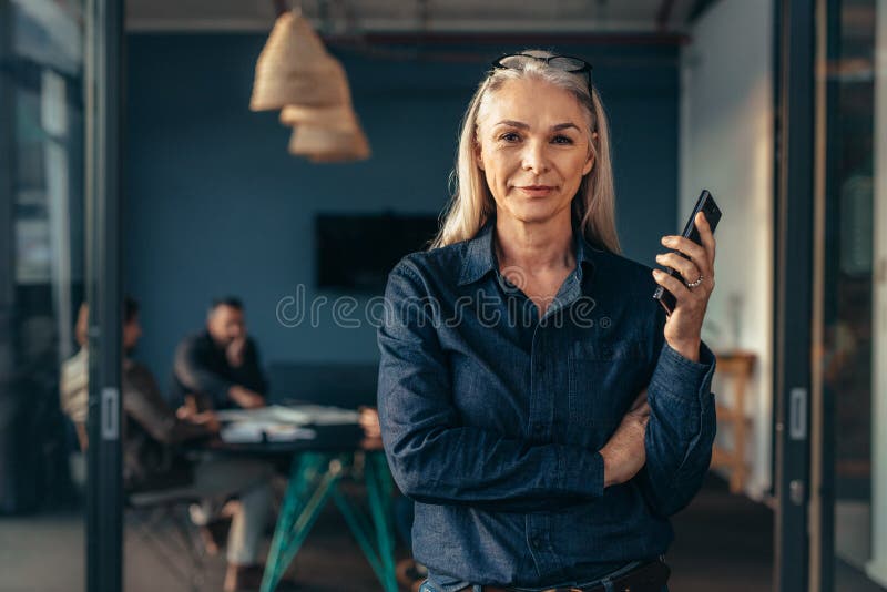 Entrepreneur réussi dans le bureau avec l'équipe au dos photos stock Entrepreneur réussi dans le bureau avec l'équipe au dos photos stock
