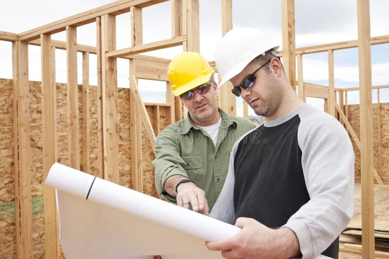 Two construction workers on the job building a home in a new housing development. Two construction workers on the job building a home in a new housing development