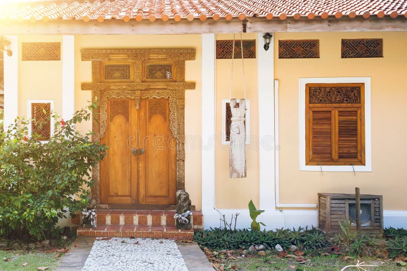Entrée à la maison jaune avec les volets découpés en bois Vieille porte en bois avec les mod?les d?coup?s Chemin en pierre menant image stock Entrée à la maison jaune avec les volets découpés en bois Vieille porte en bois avec les mod?les d?coup?s Chemin en pierre menant image stock