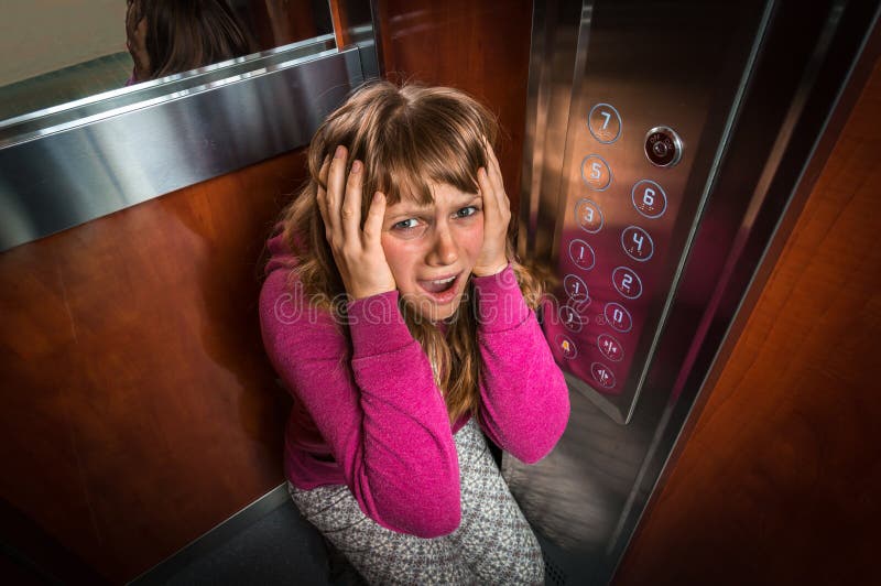 Entsetzte Frau mit Platzangst im beweglichen Aufzug stockfotografie Entsetzte Frau mit Platzangst im beweglichen Aufzug stockfotografie