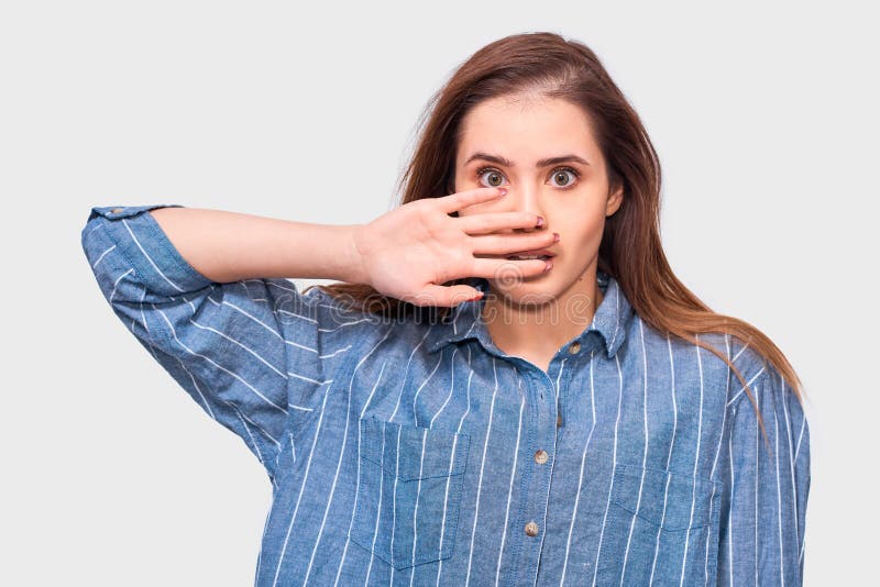 Entsetzte junge Frau trägt das zufällige gestreifte blaue Hemd und betrachtet die Kamera, lokalisiert auf weißem Studiohintergrun stockbilder Entsetzte junge Frau trägt das zufällige gestreifte blaue Hemd und betrachtet die Kamera, lokalisiert auf weißem Studiohintergrun stockbilder