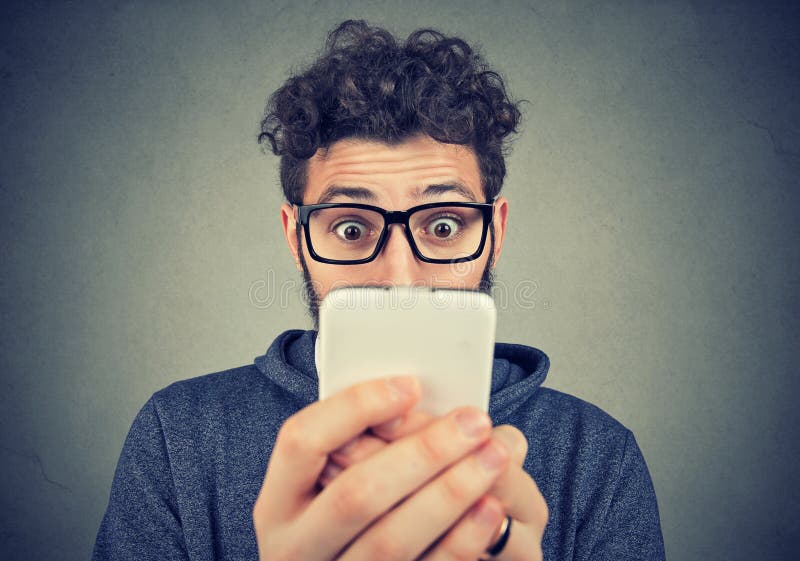 Entsetzter junger Mann, der Smartphone betrachtet stockfotos Entsetzter junger Mann, der Smartphone betrachtet stockfotos