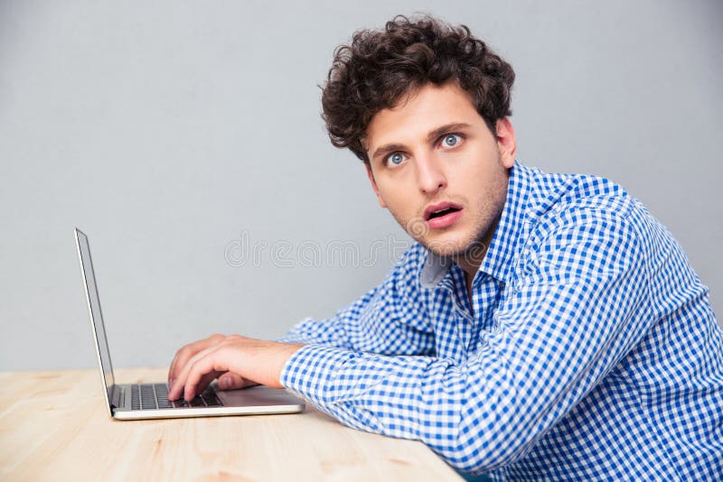 Entsetzter Mann, der am Tisch mit Laptop sitzt