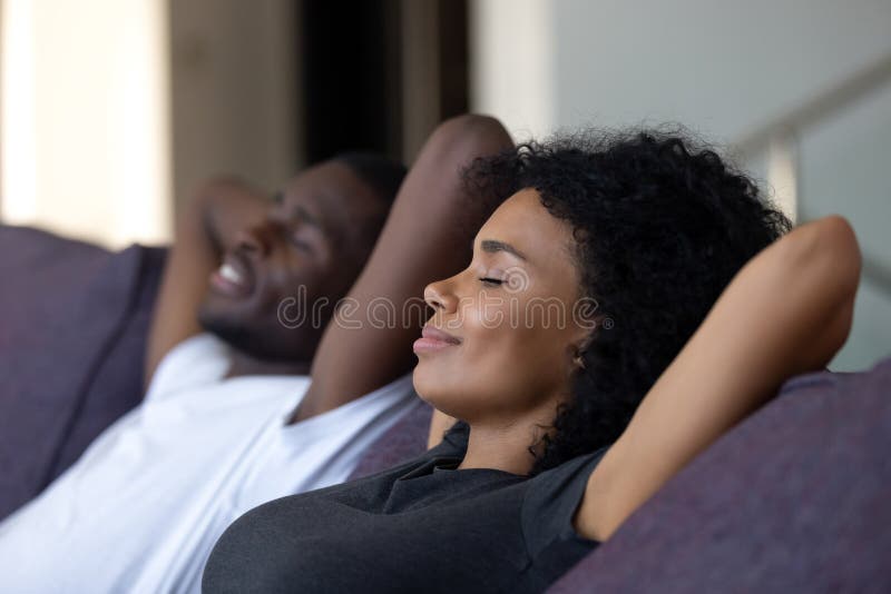 Entspannte afrikanische Paare, die Frischluft auf bequemer Couch atmend genießen
