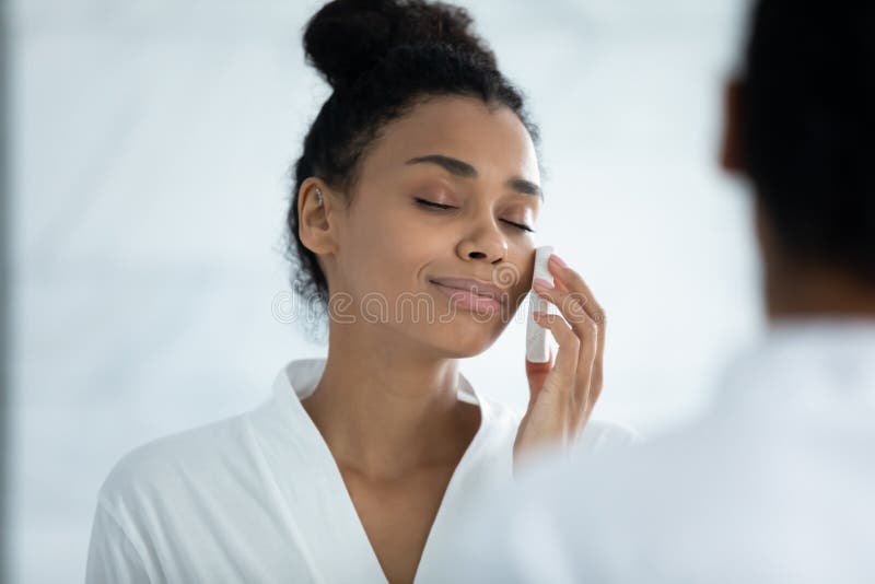 Entspannte Afroamerikanerfrau des Hauptschusses mithilfe des Gesichtsreinigungsschwammes