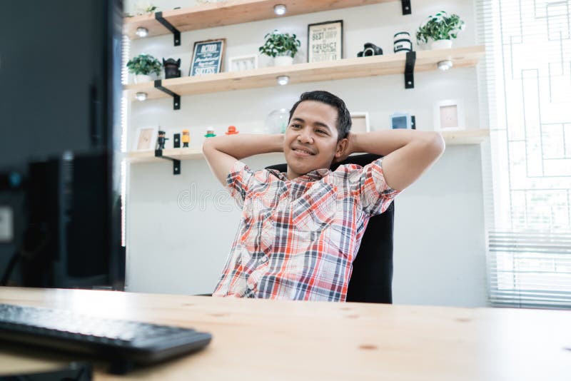 Entspannte Arbeitskraft, die auf seinen Stuhl beim Arbeiten legt lizenzfreies stockbild