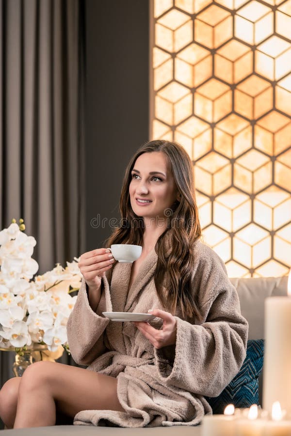 Entspannte junge Frau, die Kräutertee vor Badekur trinkt lizenzfreies stockbild Entspannte junge Frau, die Kräutertee vor Badekur trinkt lizenzfreies stockbild