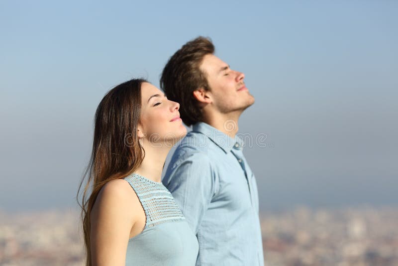 Entspannte Paare, die Frischluft mit städtischem Hintergrund atmen