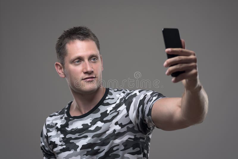 Entspannter junger erwachsener Mannesholdinghandy und nehmen Fotos oder selfie stockbild