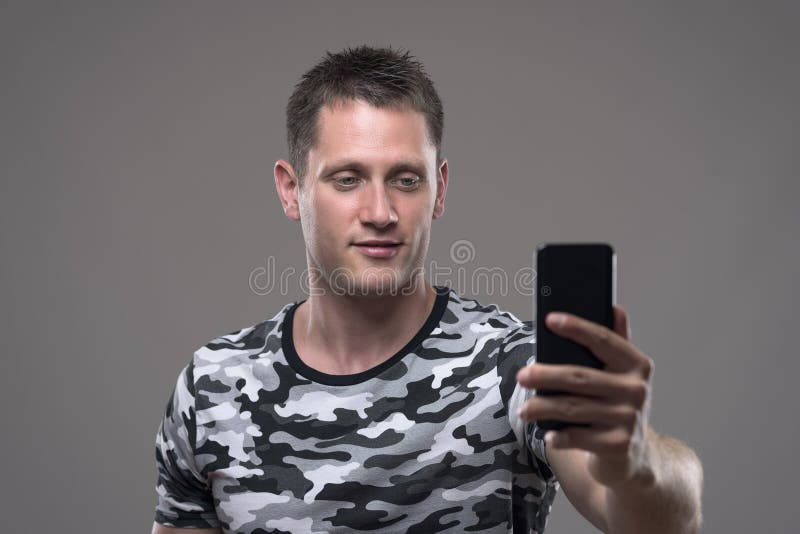 Entspannter junger erwachsener Mannesholdinghandy und nehmen Fotos oder selfie lizenzfreies stockfoto
