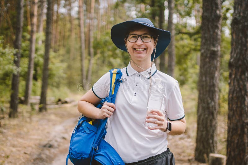 Entspannter weiblicher Tourist, der in der Natur stillsteht Gl?cklicher Frauentourist mit Rucksack Trinkwasser des touristischen lizenzfreie stockfotografie Entspannter weiblicher Tourist, der in der Natur stillsteht Gl?cklicher Frauentourist mit Rucksack Trinkwasser des touristischen lizenzfreie stockfotografie