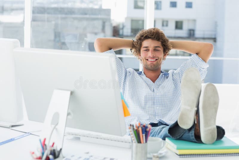 Entspannter zufälliger Mann mit den Beinen auf Schreibtisch im hellen Büro lizenzfreie stockfotografie Entspannter zufälliger Mann mit den Beinen auf Schreibtisch im hellen Büro lizenzfreie stockfotografie