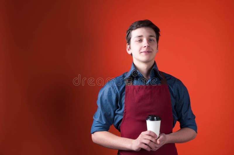 Enttäuschtes barista mit Grimasse im roten Schutzblech, das Papierschale mit Kaffee hält stockfoto Enttäuschtes barista mit Grimasse im roten Schutzblech, das Papierschale mit Kaffee hält stockfoto
