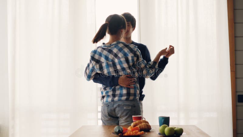 Entzückender Paarmann und -frau sind, küssend zu Hause tanzend und in der Küche, die Freizeitbekleidung Zeit zusammen genießend t