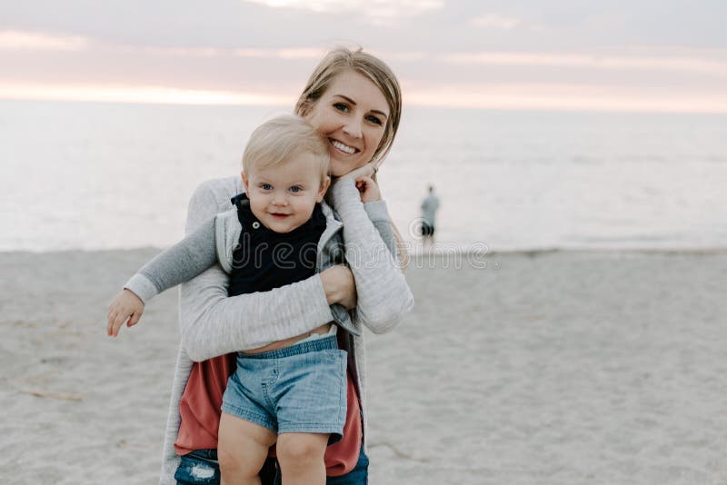 Entzückend perfekte junge Mutter-und Baby-Kleinkind-Sohn-Familie, die bei Sandy Beach During Sun lacht, lächelt und sich hält lizenzfreies stockfoto Entzückend perfekte junge Mutter-und Baby-Kleinkind-Sohn-Familie, die bei Sandy Beach During Sun lacht, lächelt und sich hält lizenzfreies stockfoto