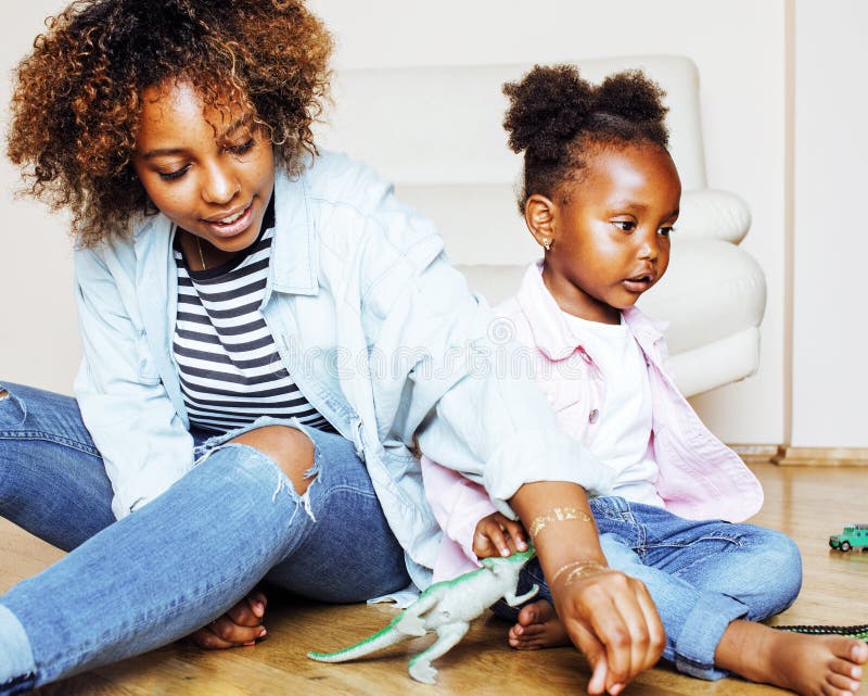 Bezaubernde, liebevolle junge afroamerikanische Mutter mit einer süßen kleinen Tochter, zu Hause beim Spaß haben, Spielen und Läch lizenzfreies stockfoto