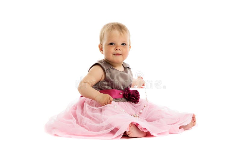 Entzückendes kleines Baby im rosa Kleid, das auf Boden sitzt