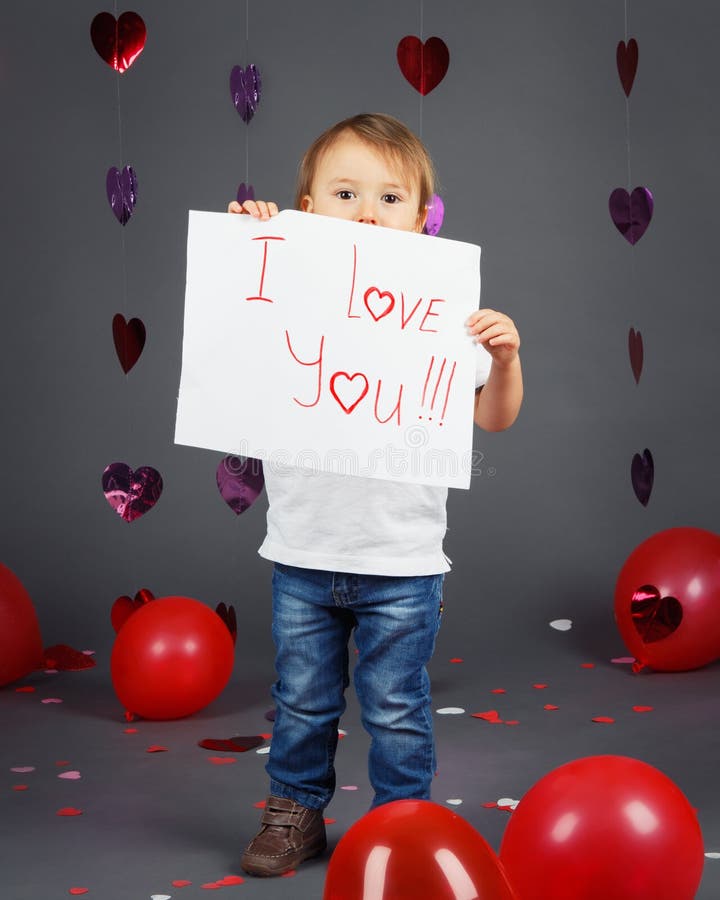 Entzückendes kleines weißes kaukasisches blondes Jungenkleinkind im Studio mit roten Herzen und Ballonen auf grauem Hintergrund lizenzfreie stockfotos Entzückendes kleines weißes kaukasisches blondes Jungenkleinkind im Studio mit roten Herzen und Ballonen auf grauem Hintergrund lizenzfreie stockfotos