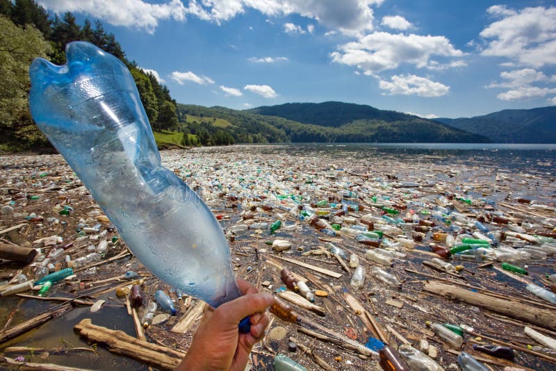 Mano gettando la bottiglia di plastica in un meraviglioso paesaggio rovinato dall'inquinamento, dal lago di bicaz romania.