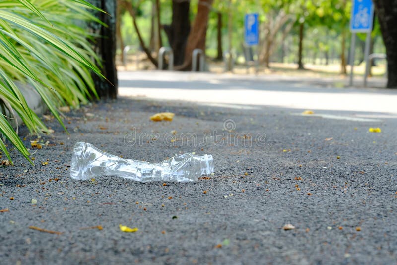 A plastic bottle of drinking water littering on the road ground floor at the park with blur green nature background royalty free stock image A plastic bottle of drinking water littering on the road ground floor at the park with blur green nature background royalty free stock image