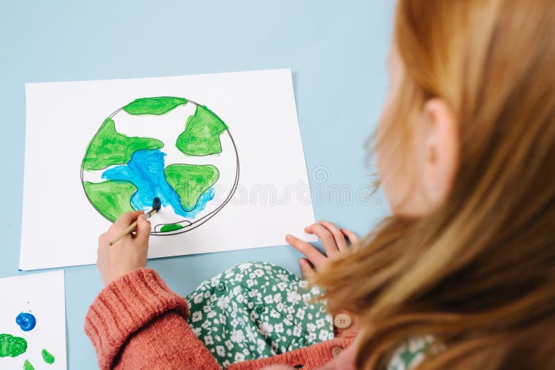 An environmental concept. Girl paints a picture of green land