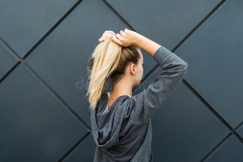 Epic back view of strong fit female athlete getting ready for workout towards the sun. Strong fitness woman tying ponytail. Motiva stock images Epic back view of strong fit female athlete getting ready for workout towards the sun. Strong fitness woman tying ponytail. Motiva stock images